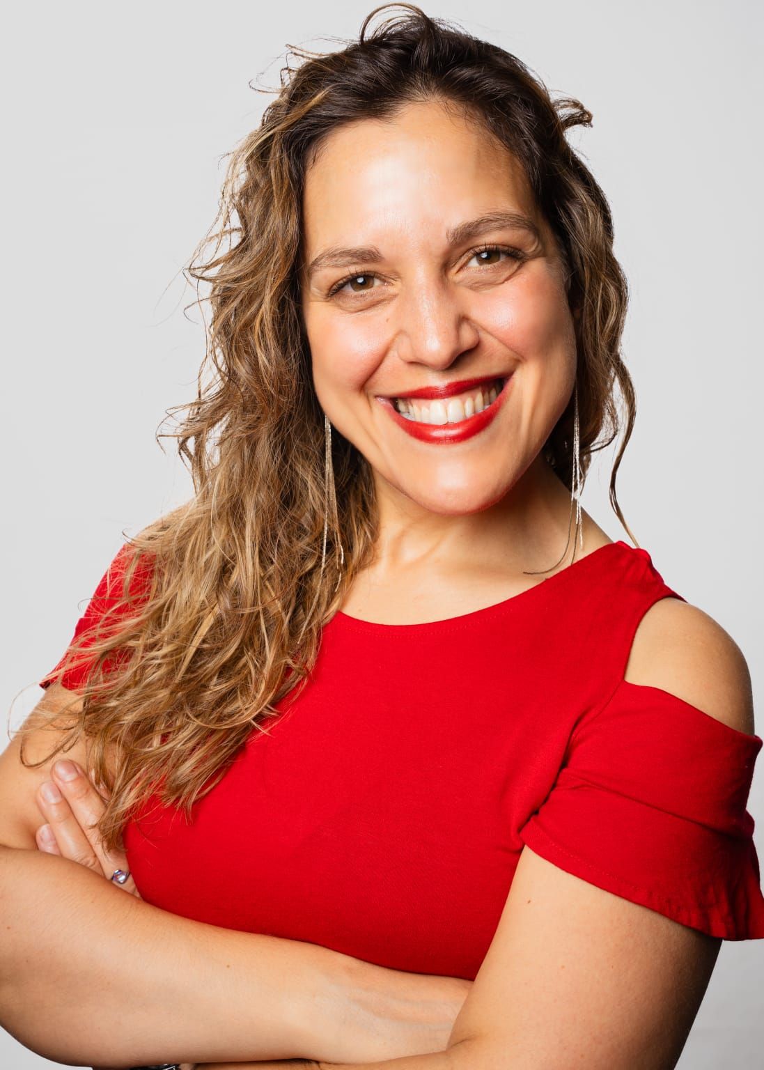 Roberta Nozzolillo im roten Oberteil, die Arme verschränkt, lacht in die Kamera